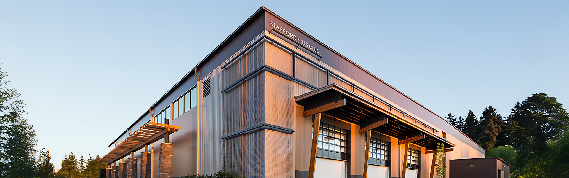 steel facade with horizontal panel reveals, deep roof overhang, and exposed timber brackets